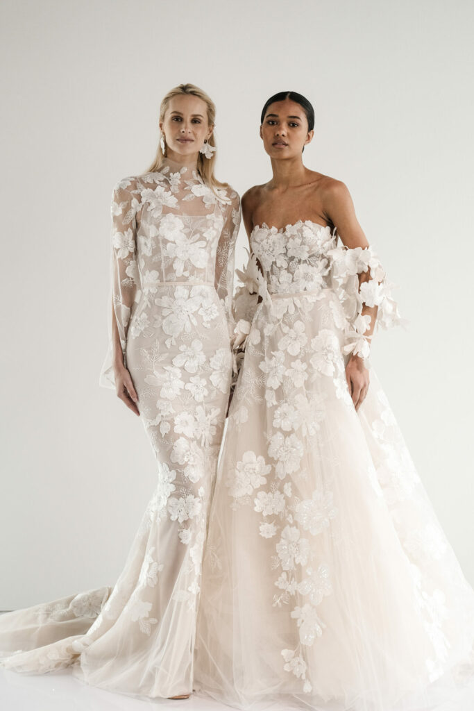 Two women in floral lace wedding dresses, contrasting sleeves.