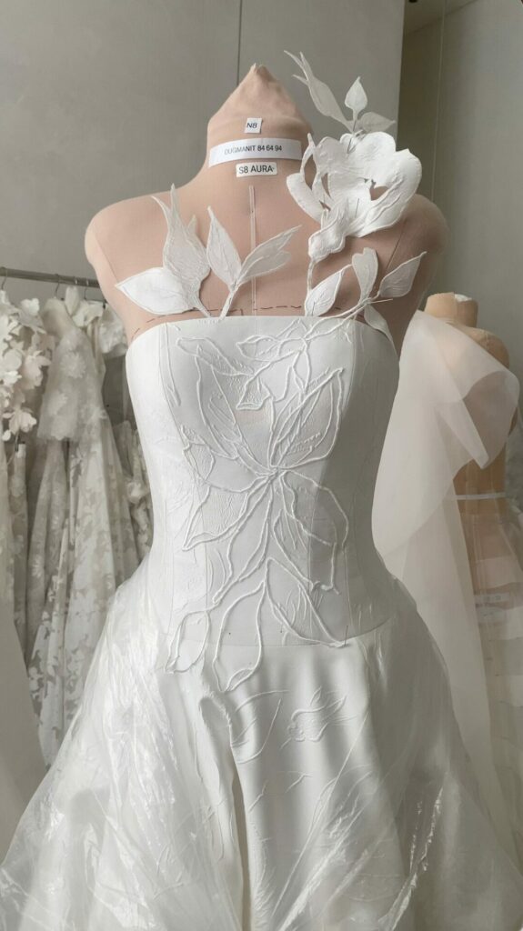 White strapless gown with 3D floral appliqué displayed.