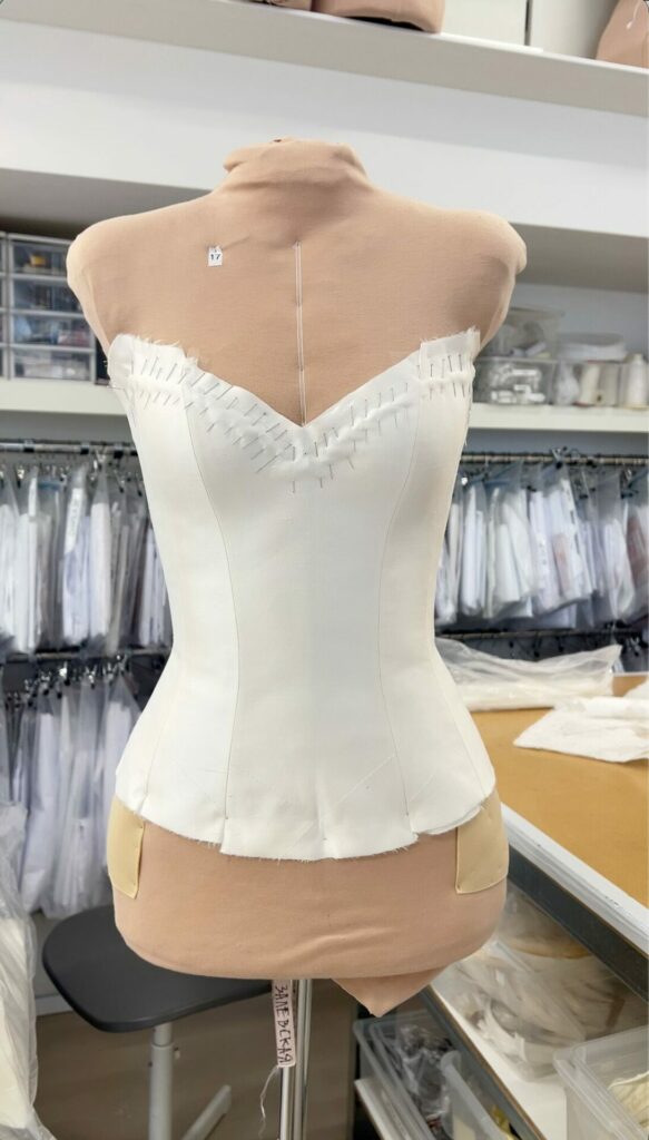 White corset on beige dress form in studio.