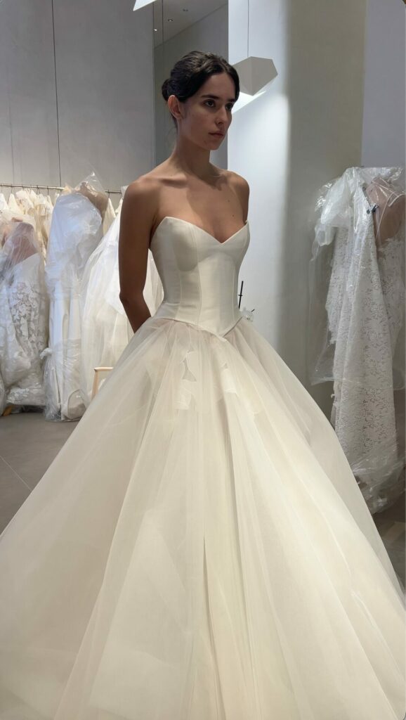 Woman in strapless white wedding dress at bridal shop.