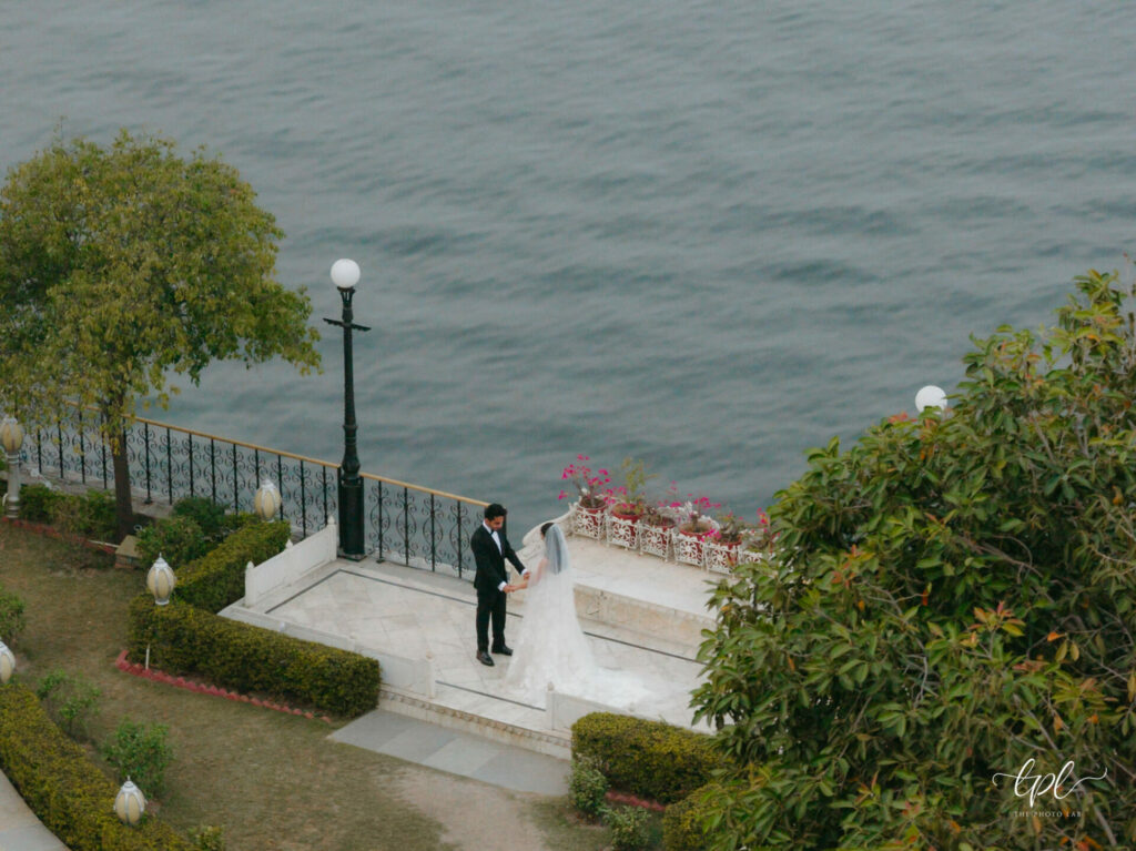 Bride and groom hold hands on floral white terrace.