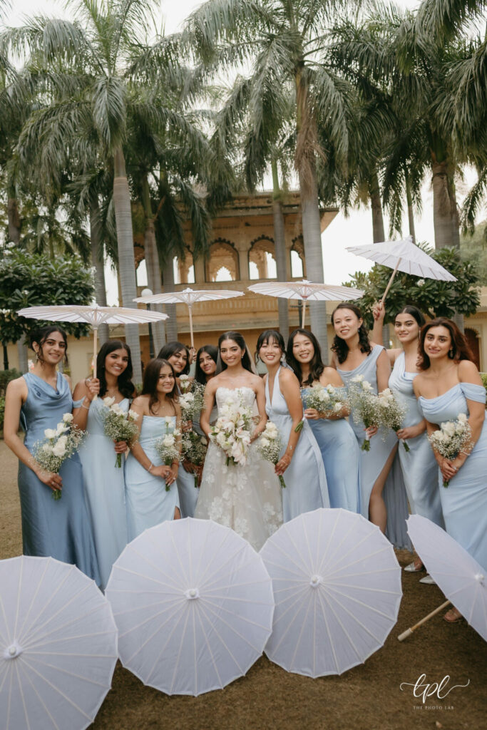 Bride and bridesmaids pose outside with parasols.