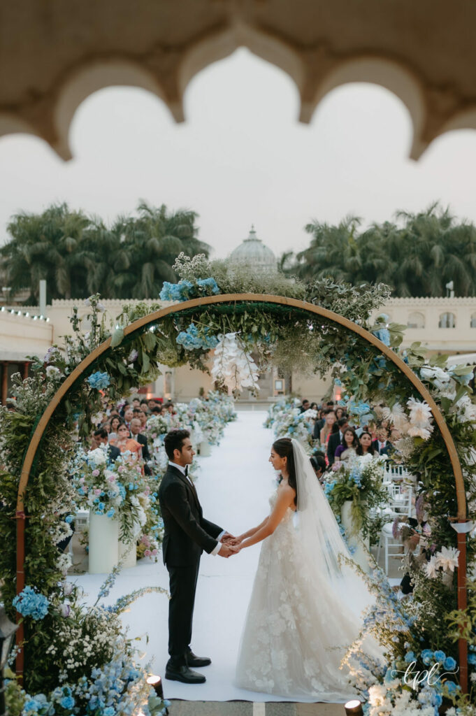 Bride and groom under floral arch at outdoor wedding.