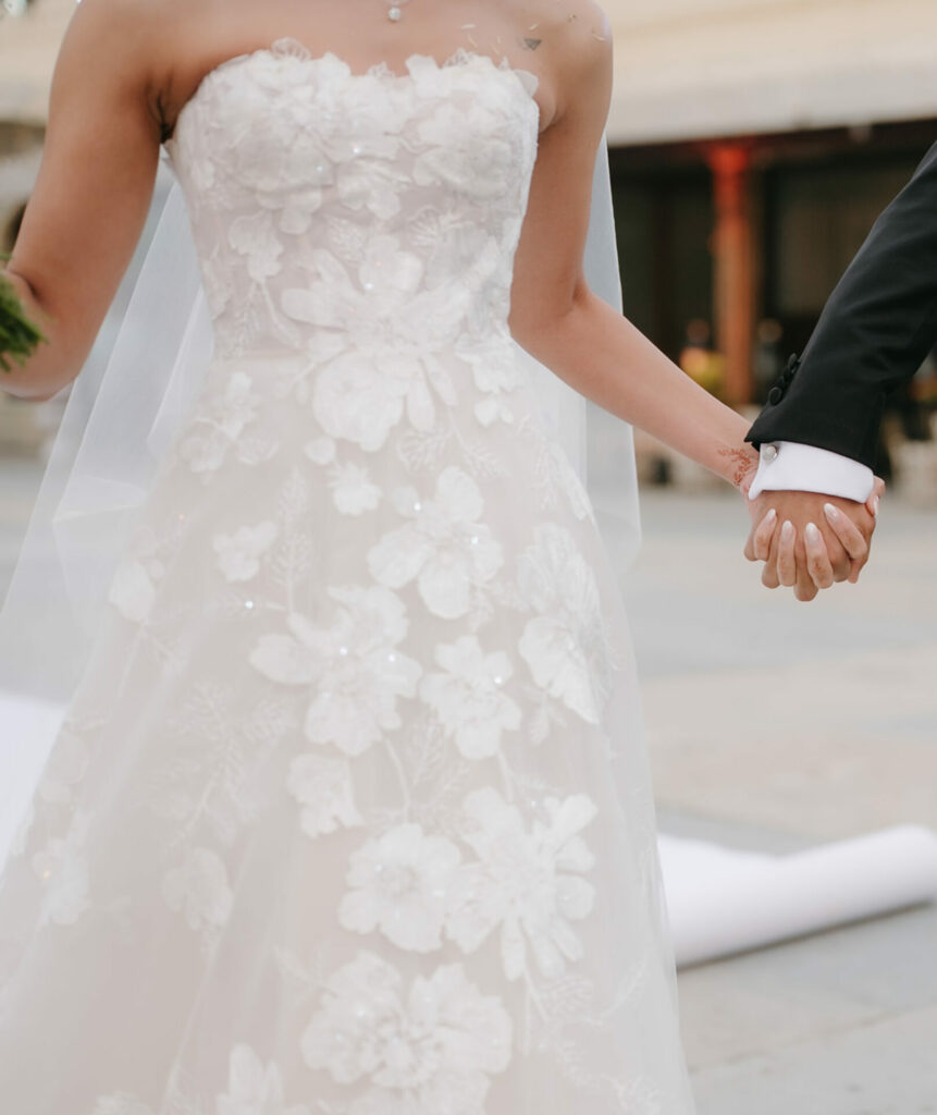 Bride and groom holding hands, bride’s lace dress.