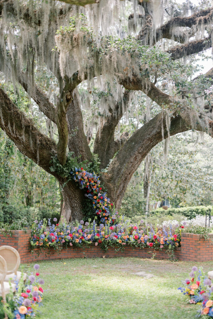 Flower-decorated mossy oak tree in bridal garden.