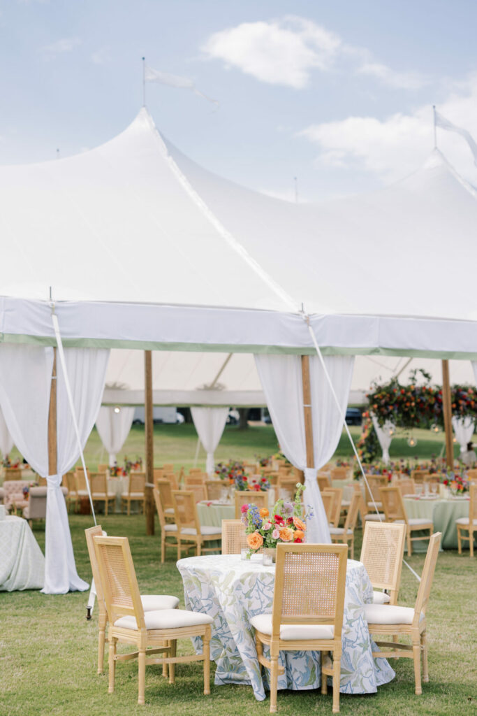 Elegant outdoor wedding under white tent, floral tables.