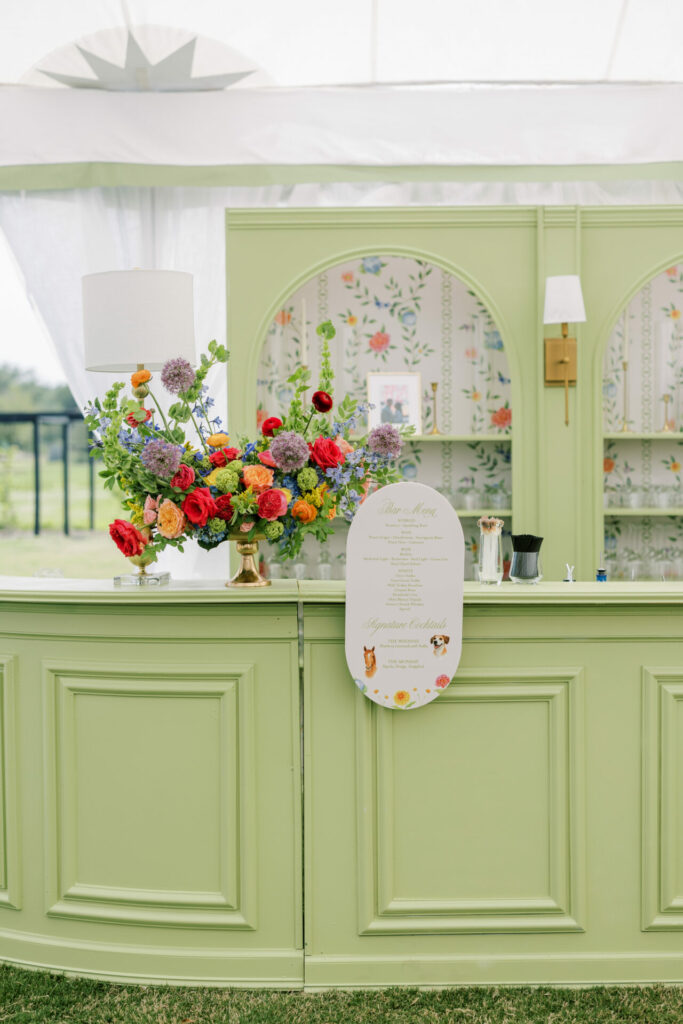 Pastel green floral bar with flowers under tent.