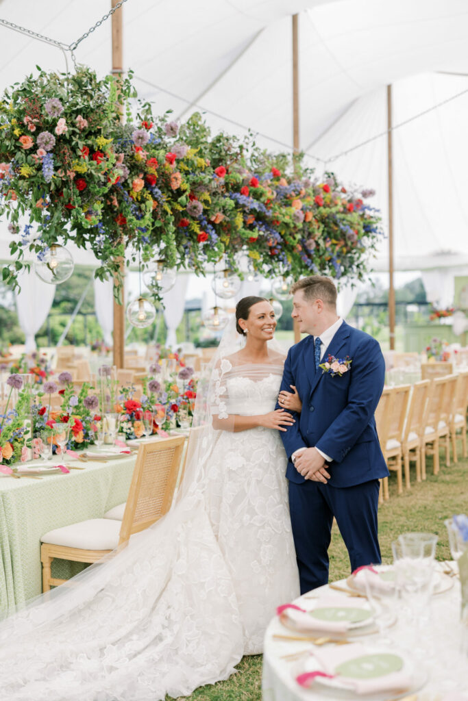 Bride and groom smiling amid elegant floral decor.