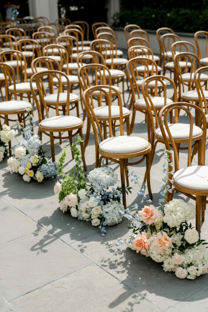 Outdoor wedding chairs with pastel aisle flowers.