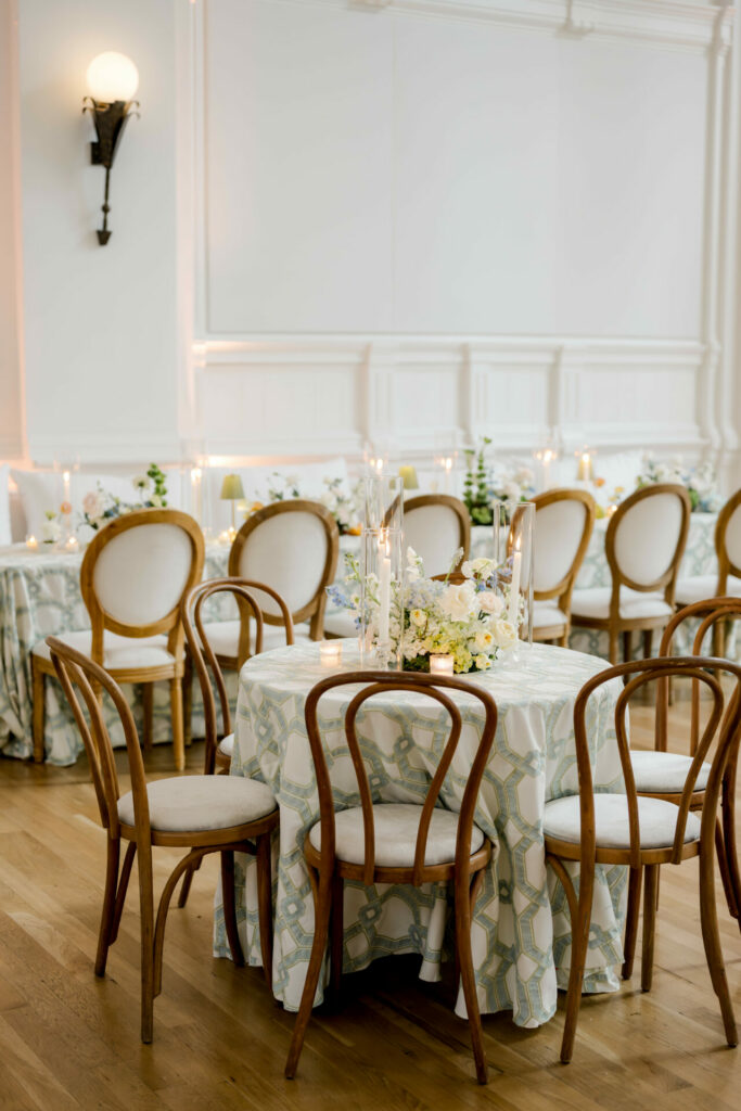 Elegant round table with flowers, candles, wooden chairs.