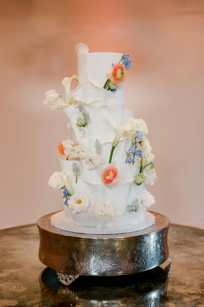 Elegant white wedding cake with ruffles and flowers.