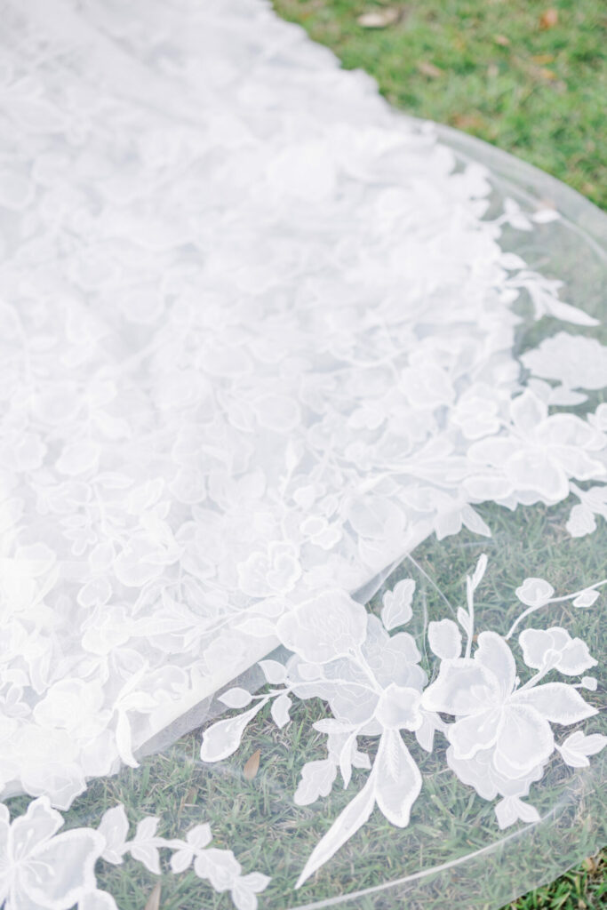 White lace wedding dress train on green grass.