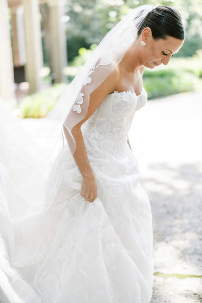 Smiling bride in strapless lace gown outdoors.