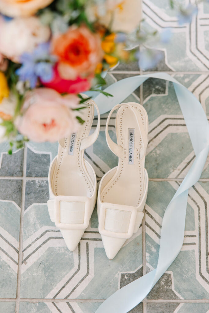 Heels, flowers, and ribbon on patterned tiles.