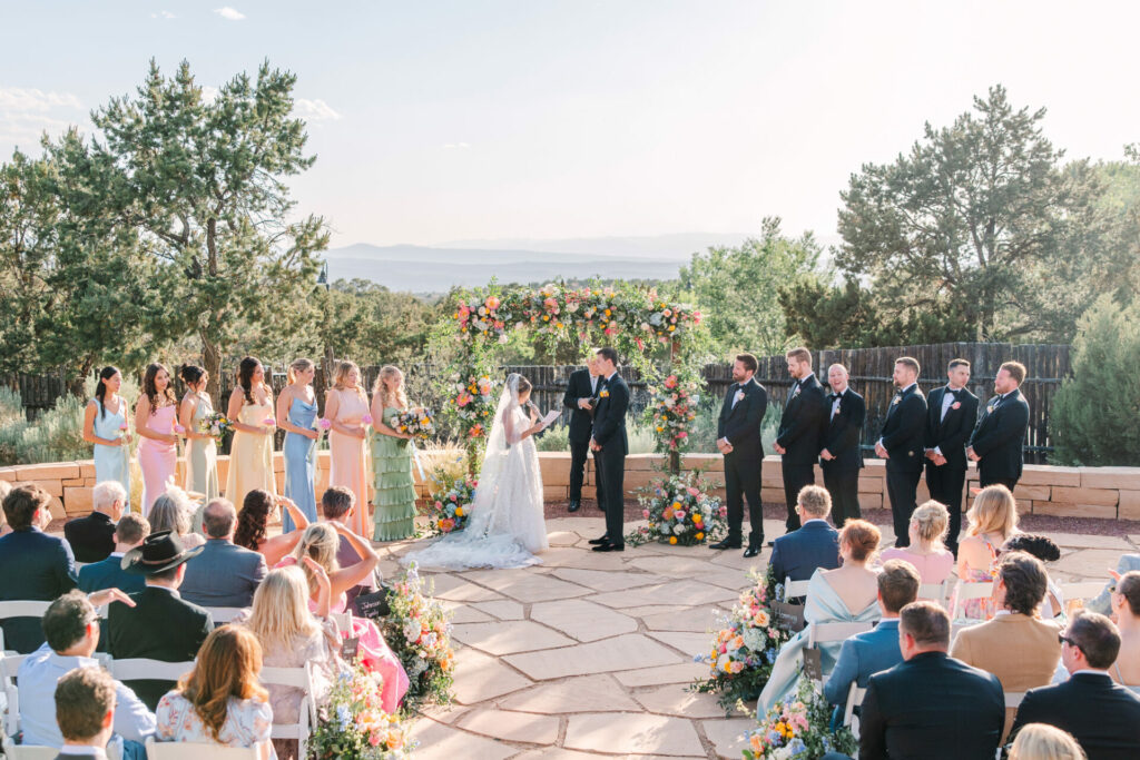 Bride and groom under floral arch at luxury wedding.