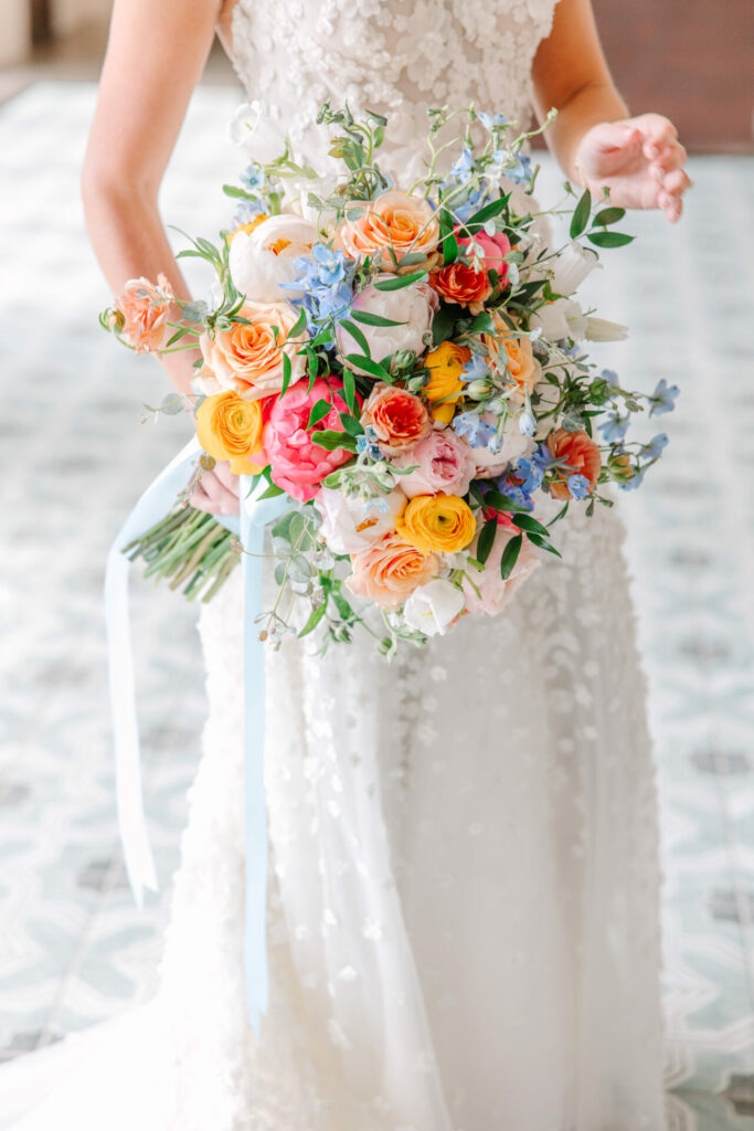 Bride with vibrant bouquet and flowing ribbon.