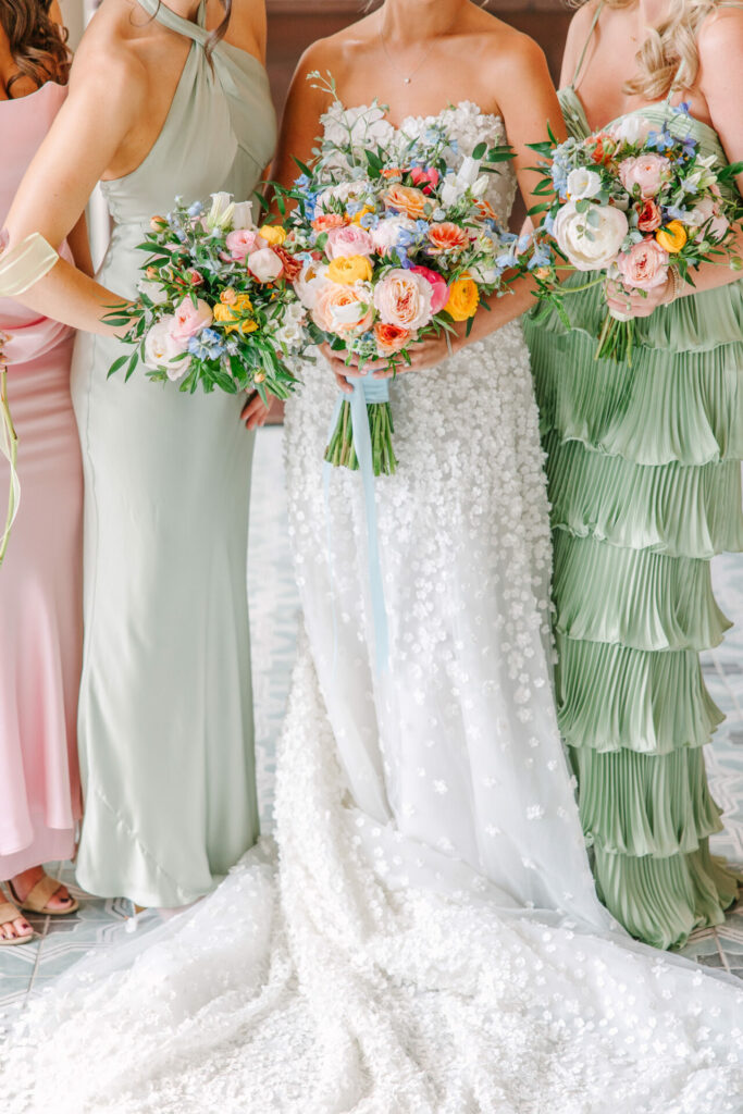 Pastel-dressed women with bouquets; center in white gown.