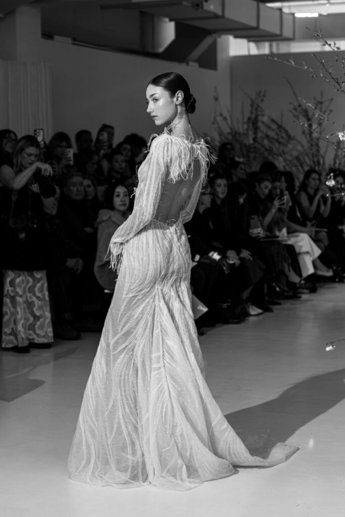 Model wearing the sheer Anouka wedding dress by Mira Zwillinger on the runway