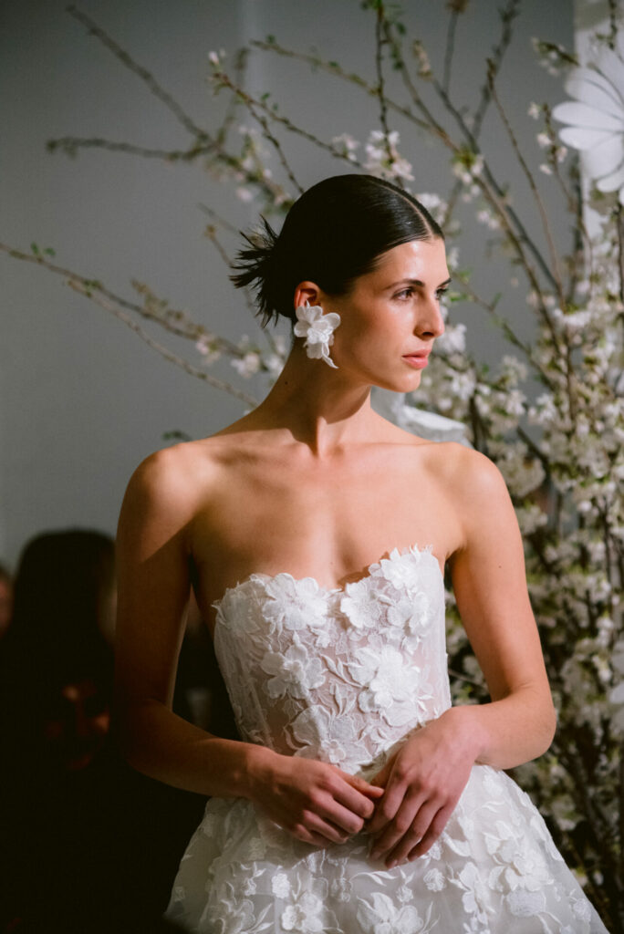 Bride in a hand-embroidered floral Mira Zwillinger wedding dress among blossoms