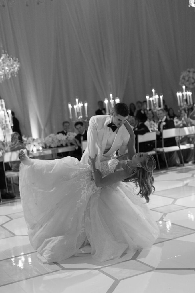 Groom dips bride in elegant, candlelit wedding reception.