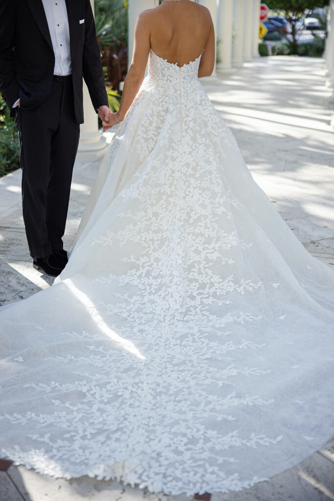 Elegant bride and groom on sunlit walkway.