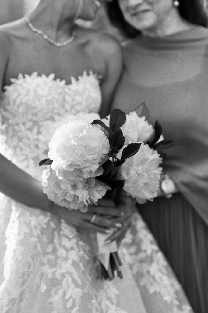 Bride in lace gown, holding bouquet, shoulders-down view.