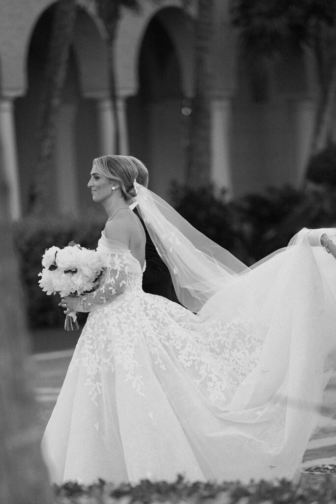 Bride in lace gown, outdoors, black-and-white.