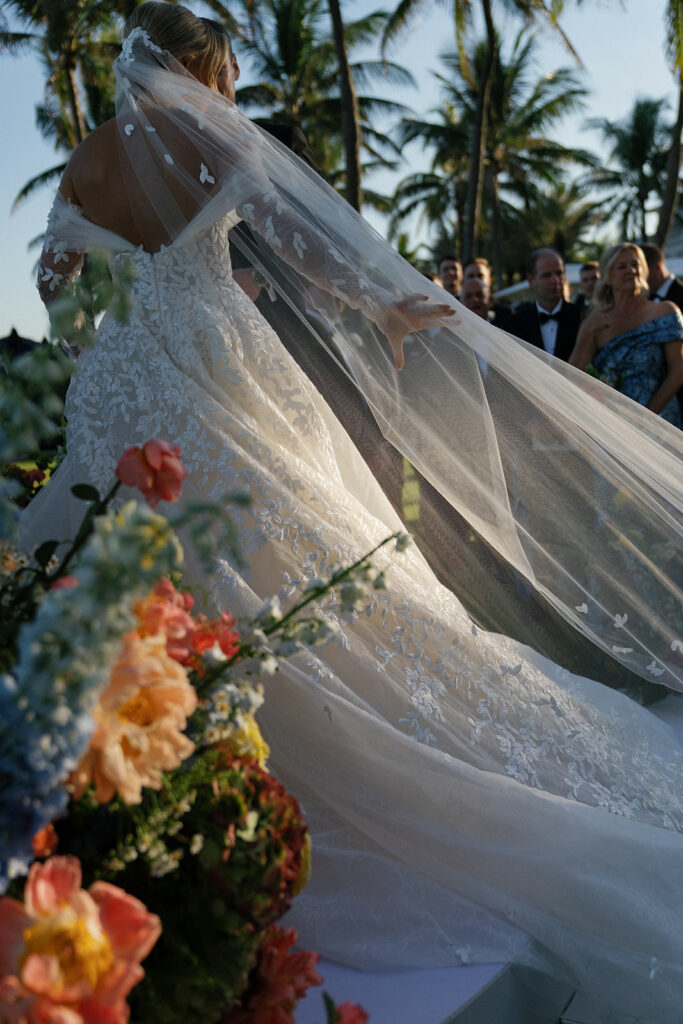 Bride in lace gown outdoors, luxury wedding scene.
