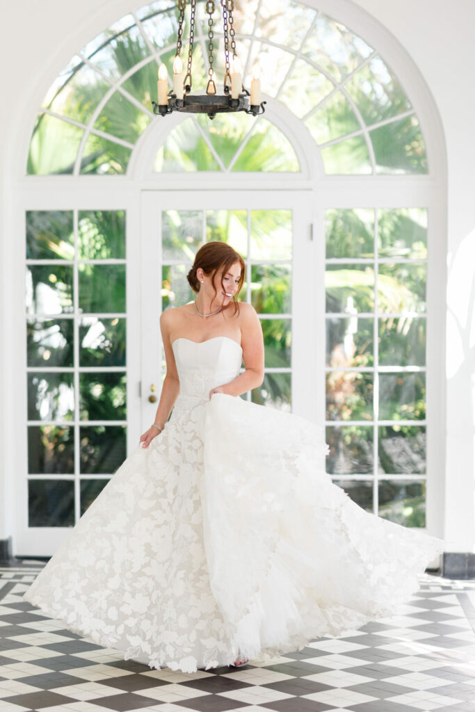 Bride in strapless white dress on checkered floor.