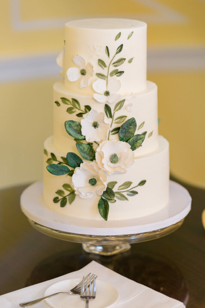 Elegant three-tier white cake with napkin, forks.
