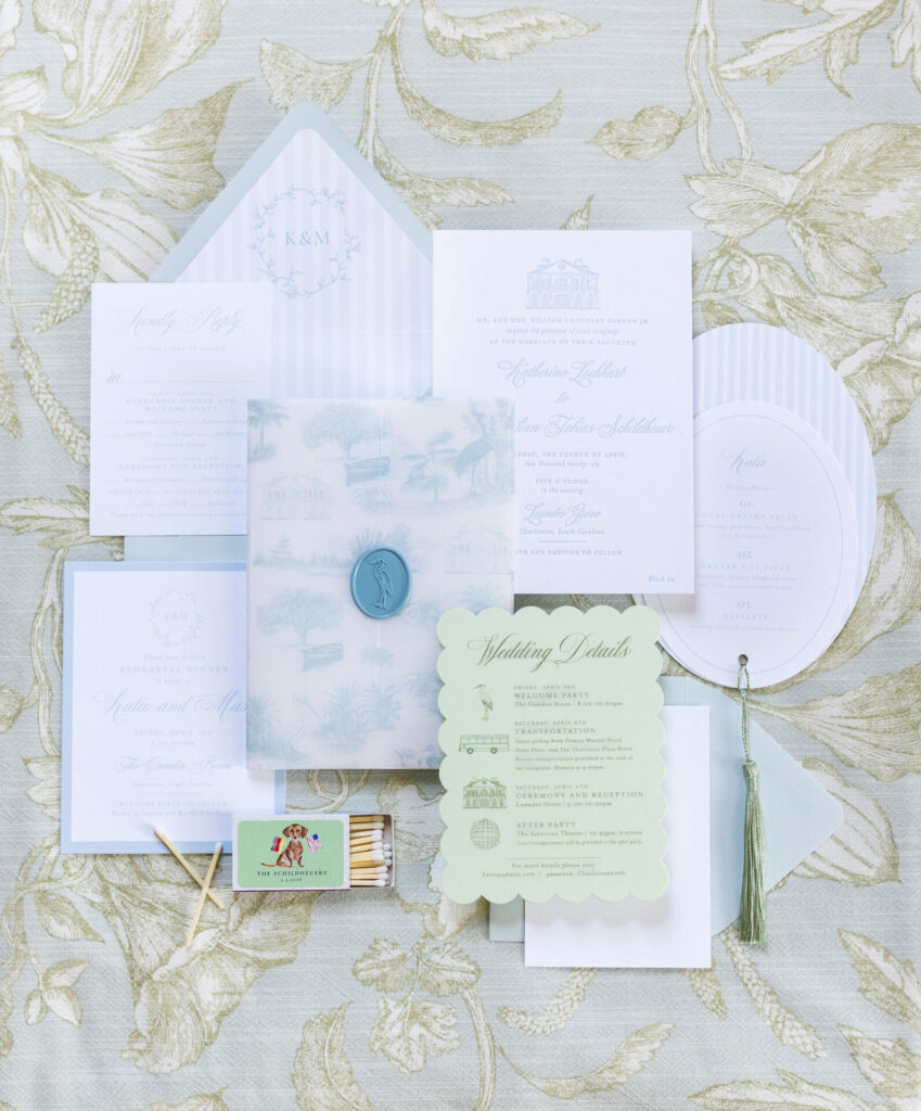 Pastel wedding stationery flat lay on patterned fabric.
