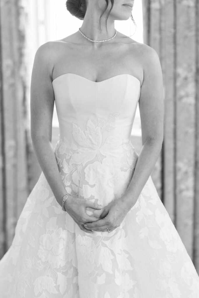 Woman in floral strapless gown, hands clasped.