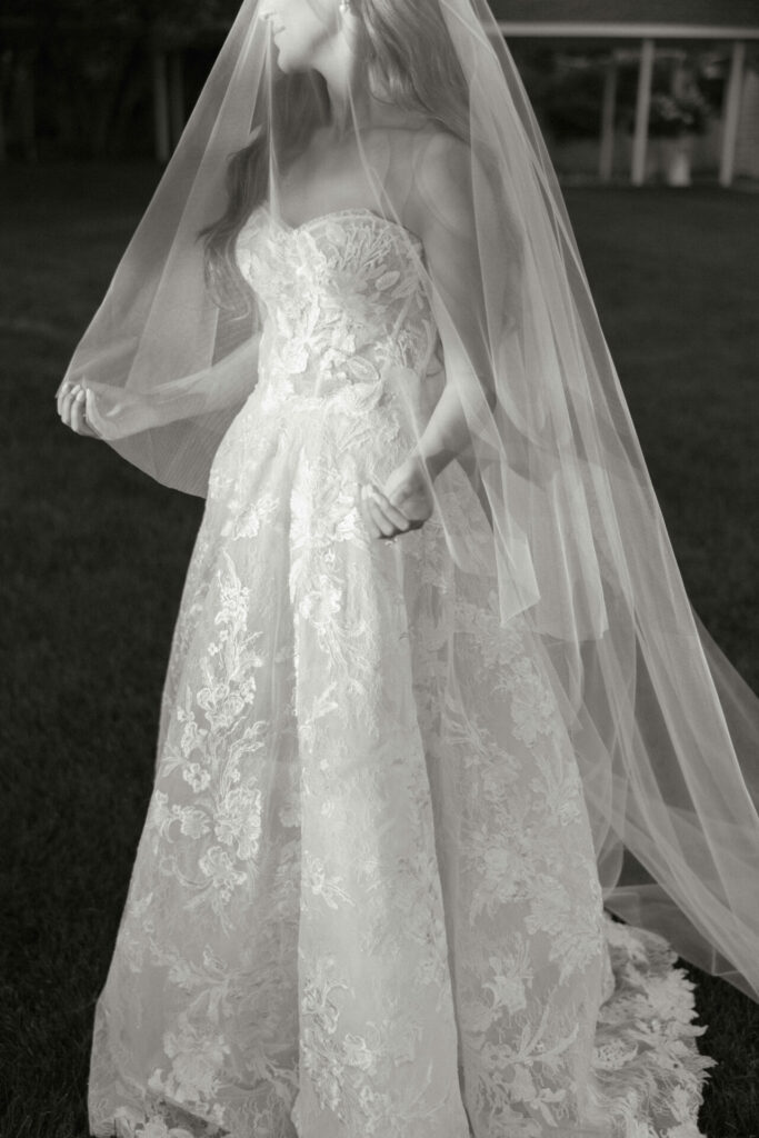 Katya Ruiz in strapless lace gown and veil outdoors.