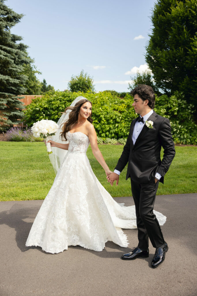 Bride and groom walk outdoors, elegant couture style.