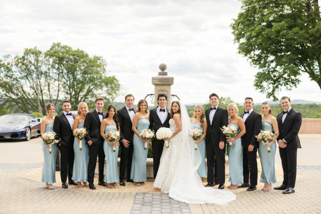 Elegant wedding party outdoors with bride, groom, and attendants.