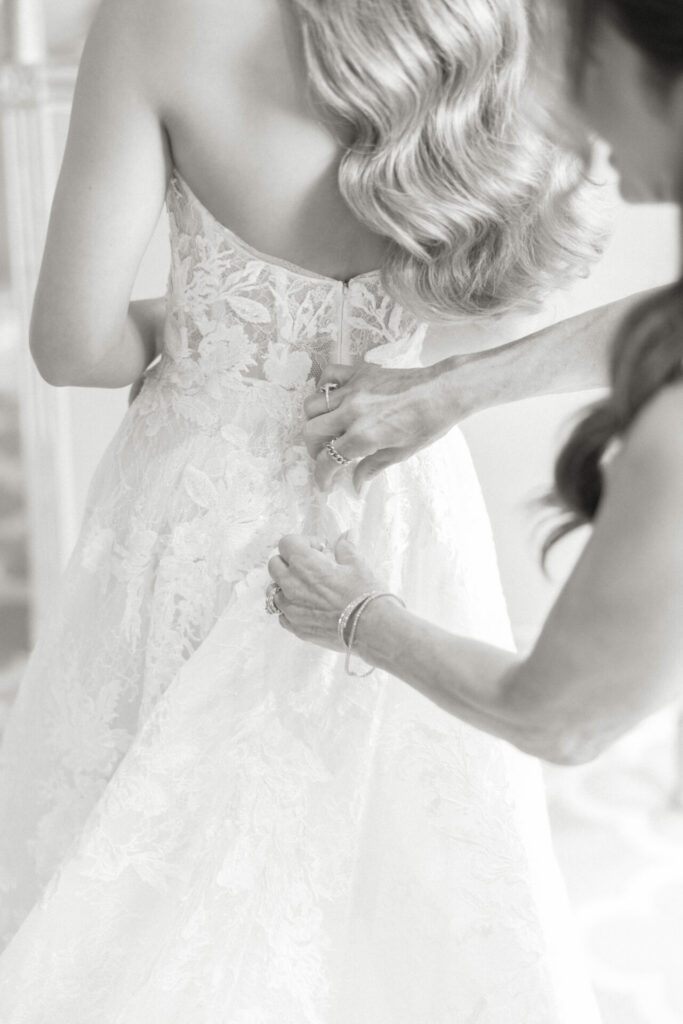 Woman fastens lace wedding dress as hair cascades.