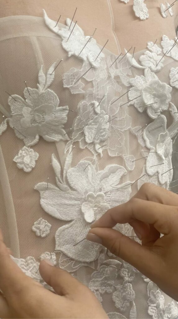 Mira Zwillinger atelier: hand-pinning lace flowers onto sheer fabric for the Alma gown