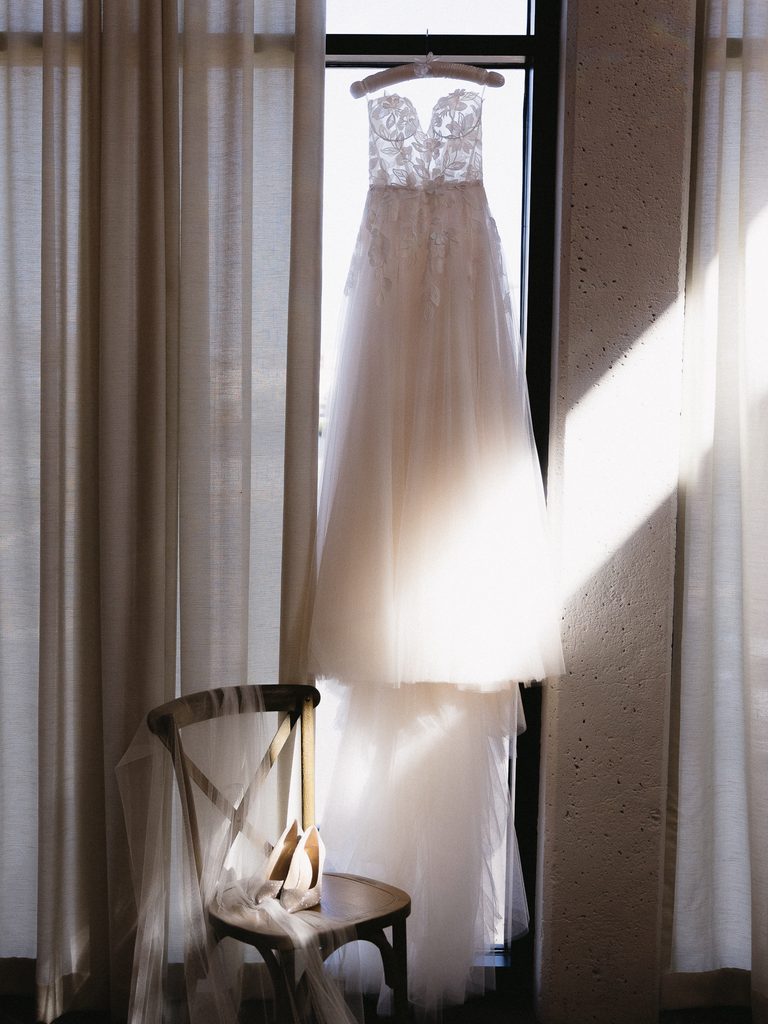 Sunlit wedding dress with veil and heels nearby.