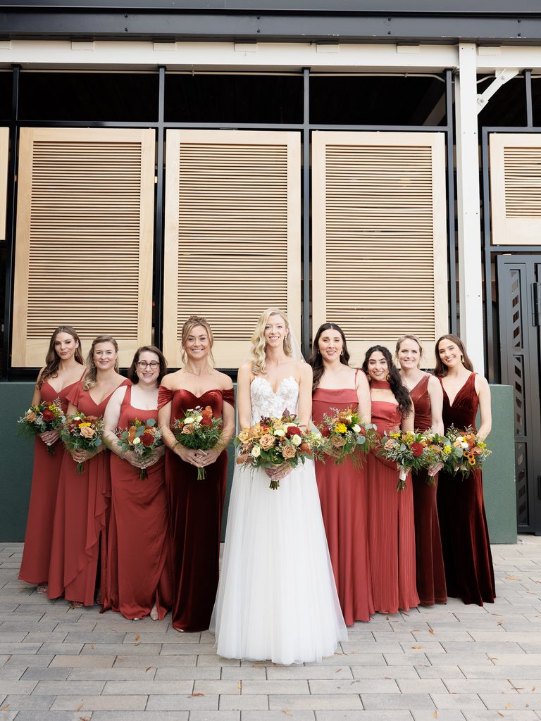 Bride and bridesmaids pose outside modern building.