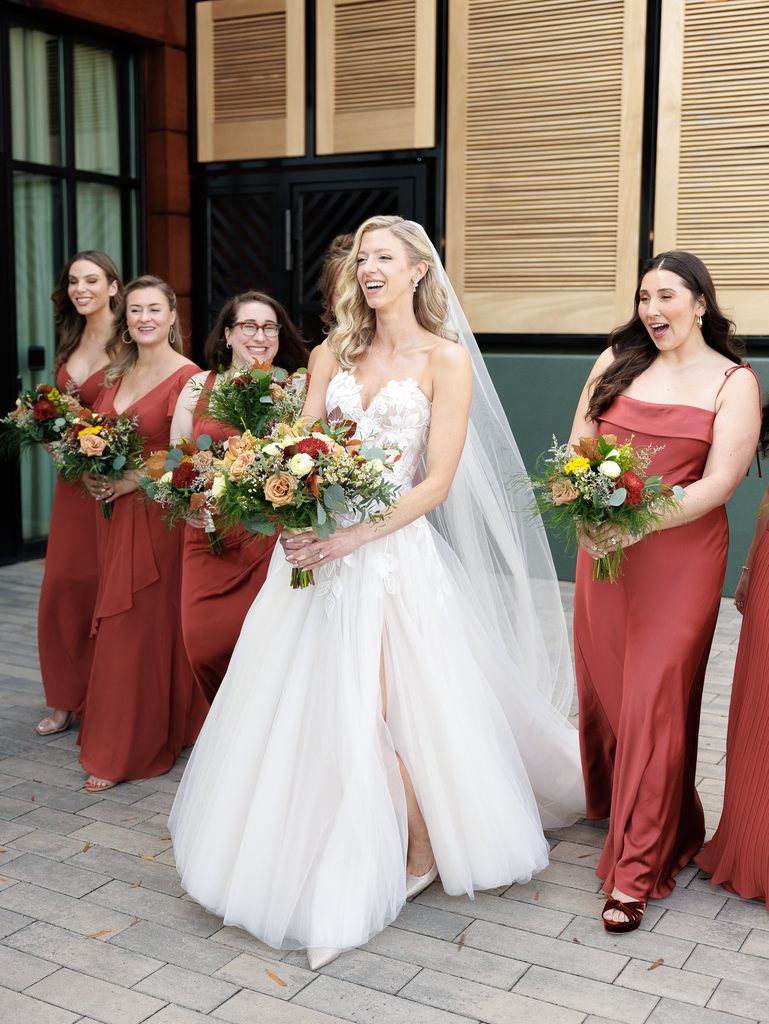 Bride and four bridesmaids with bouquets outdoors.
