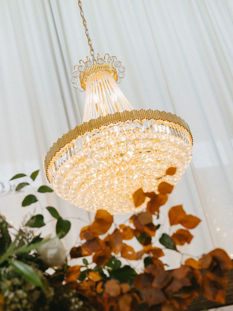 Glowing gold chandelier above soft white drapery.