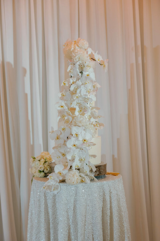 Elegant white wedding cake with orchids and drapes.