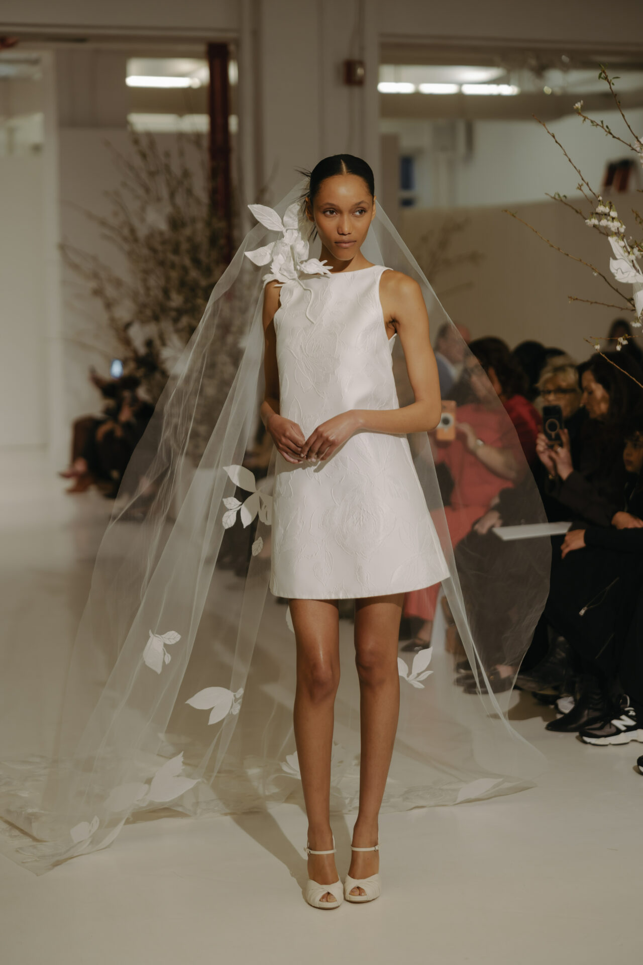Model in short white Clea dress on runway.
