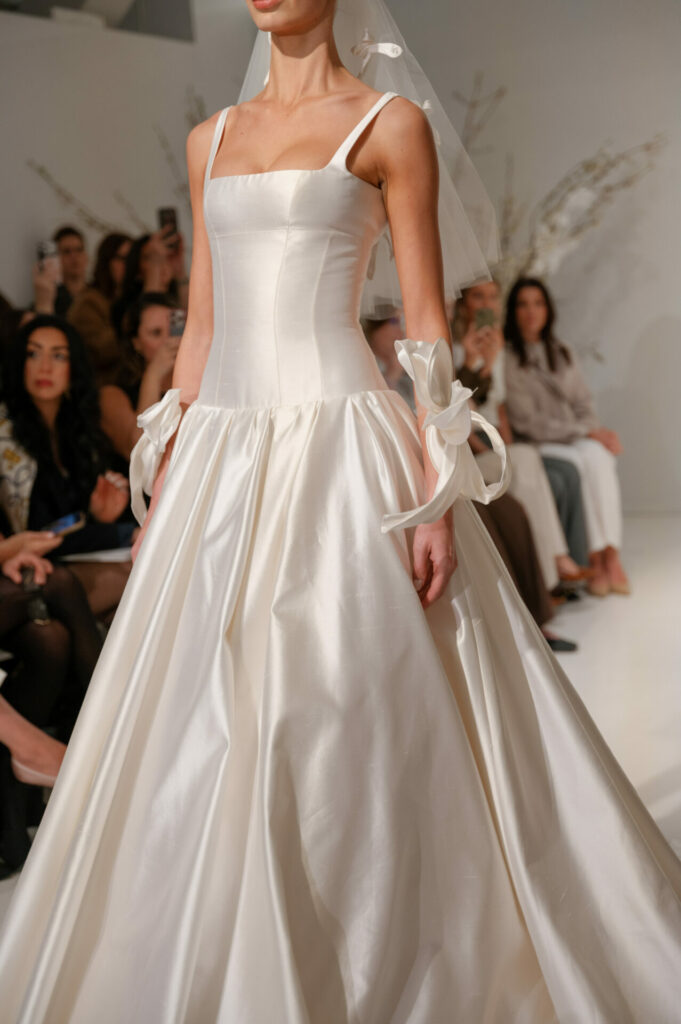 Model in Clea satin wedding dress on runway.