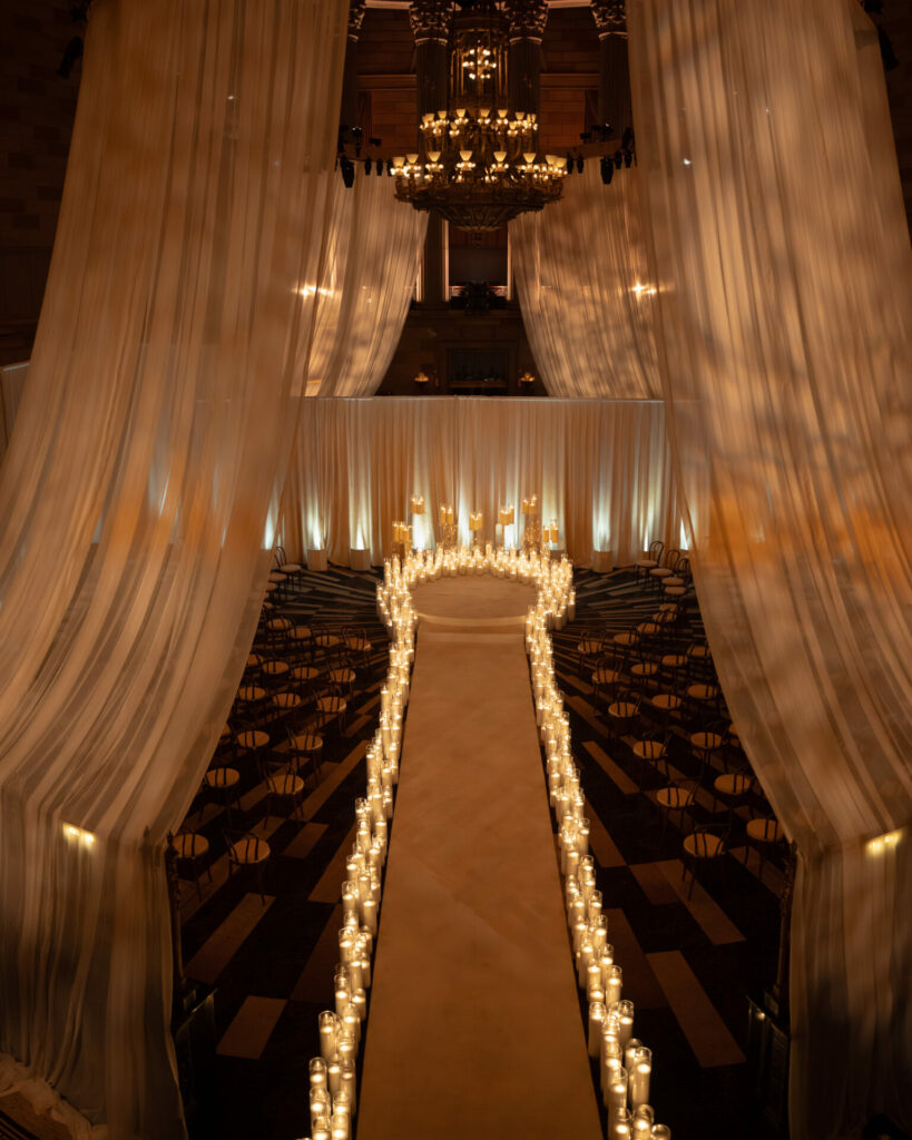 Candlelit wedding aisle, sheer drapes, grand chandelier.
