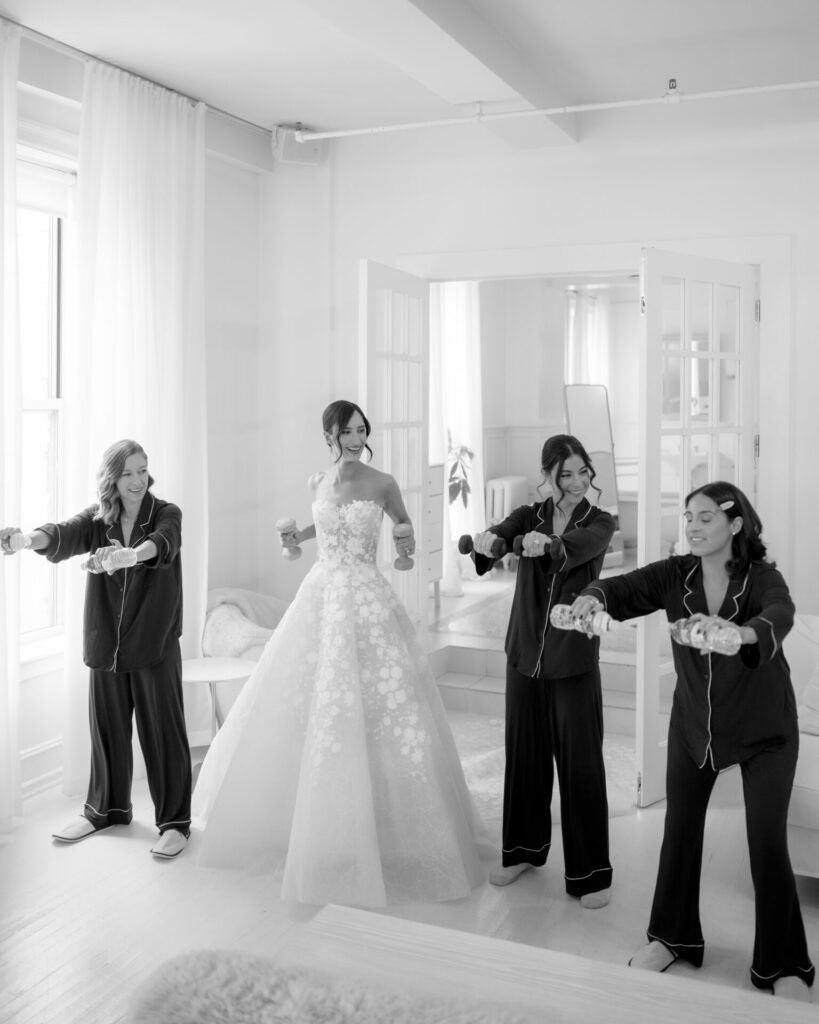 Bride in floral gown with three smiling women celebrating.