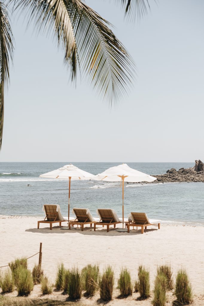 Lounge chairs, umbrellas on a luxurious beach setting.