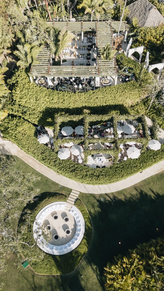 Elegant garden restaurant with white umbrellas, aerial view.