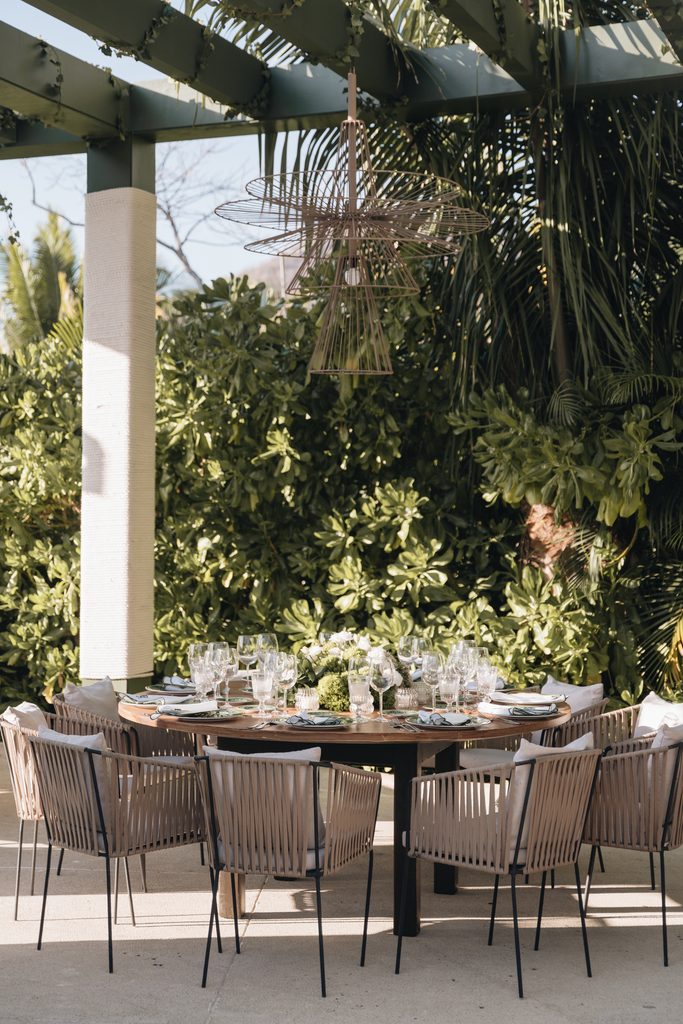 Elegant outdoor dining under pergola with greenery.