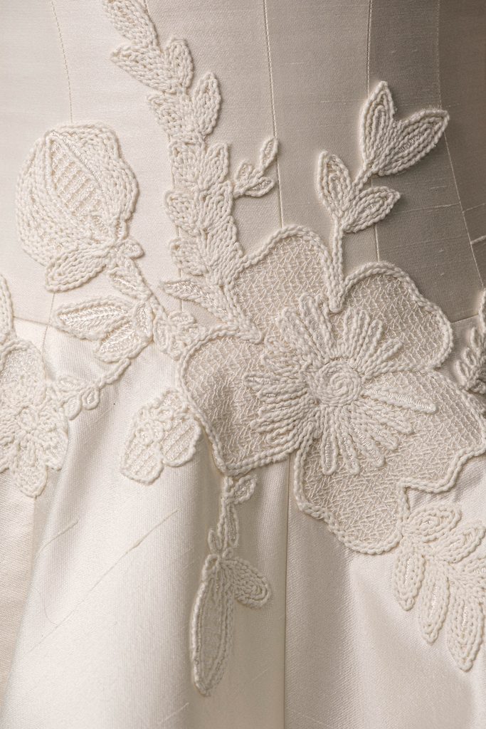 Cream fabric with elegant, embroidered floral patterns.